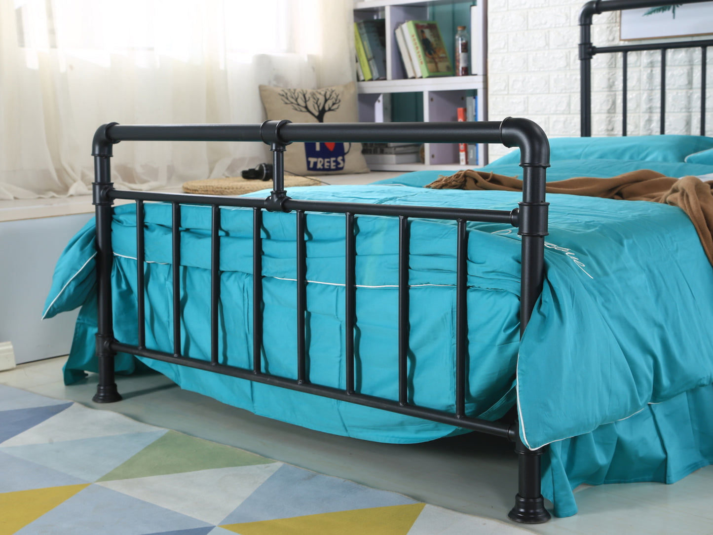 A black pipe industrial bed frame in a room with turquoise and yellow bedding, wooden slatted base, and a bookshelf in the background. | Black