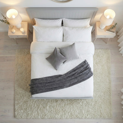 Neatly made bed with white bedding and gray throw blanket in a bedroom setting | Dove Grey