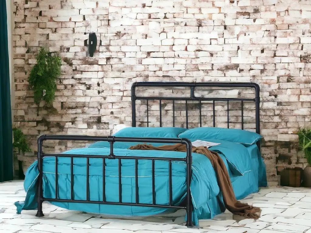 Bed with black metal frame and blue bedding against a stone wall. | Black